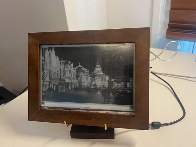 The finished e-paper picture frame, lit by the LED strip, displaying a photo